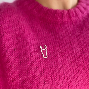 Sterling silver brooch in the shape of a hroses head in a conterporay style with clean graphic lines worn on a pink knit.